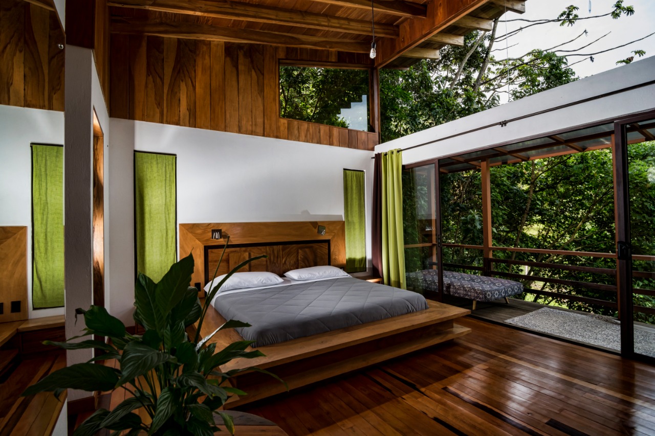 Dormitorio de Casa Ficus con acabados en madera, cortinas verdes y salida a la terraza