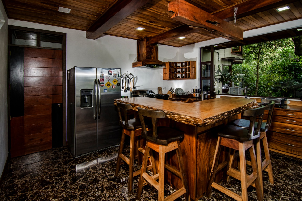 Cocina full equipada de Casa Ficus con barra de madera de una sola pieza y taburetes