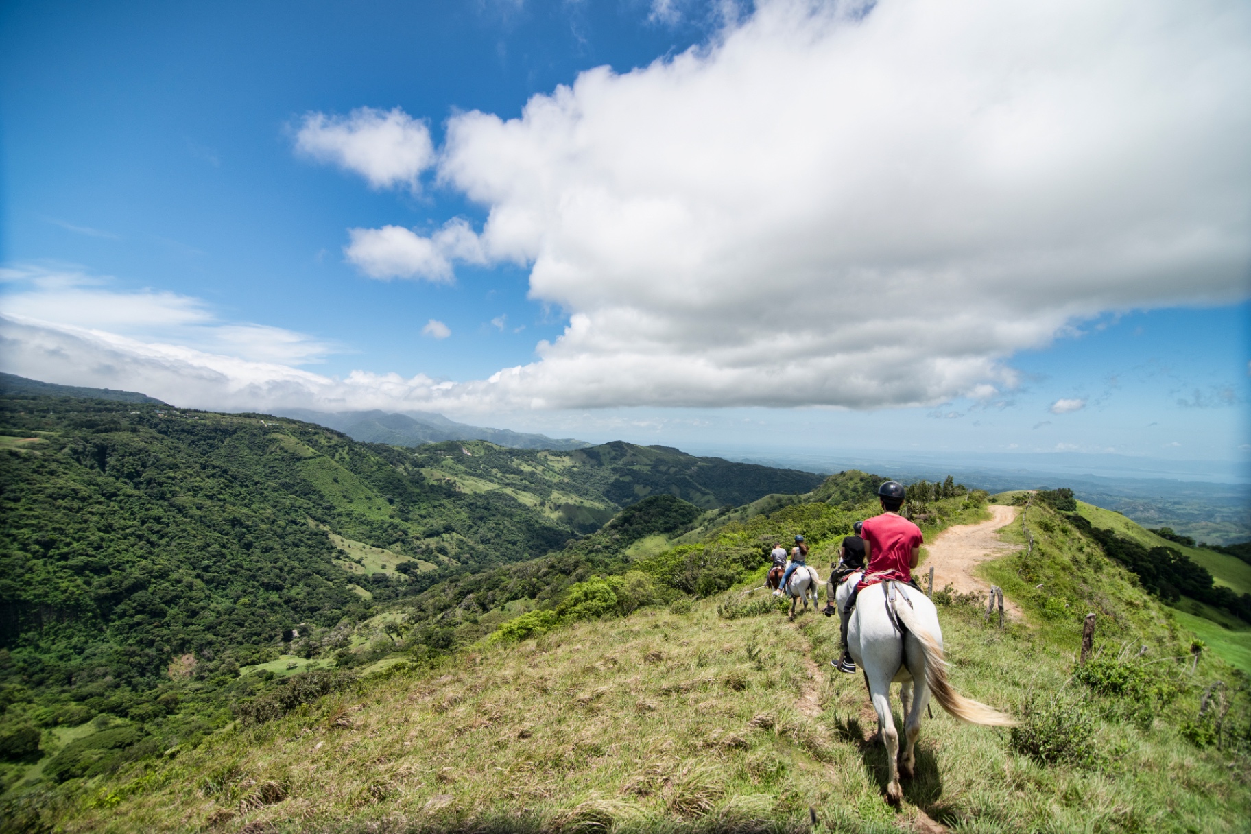 Huéspedes recorriendo a caballo un sendero de montaña entre el valle de Monteverde