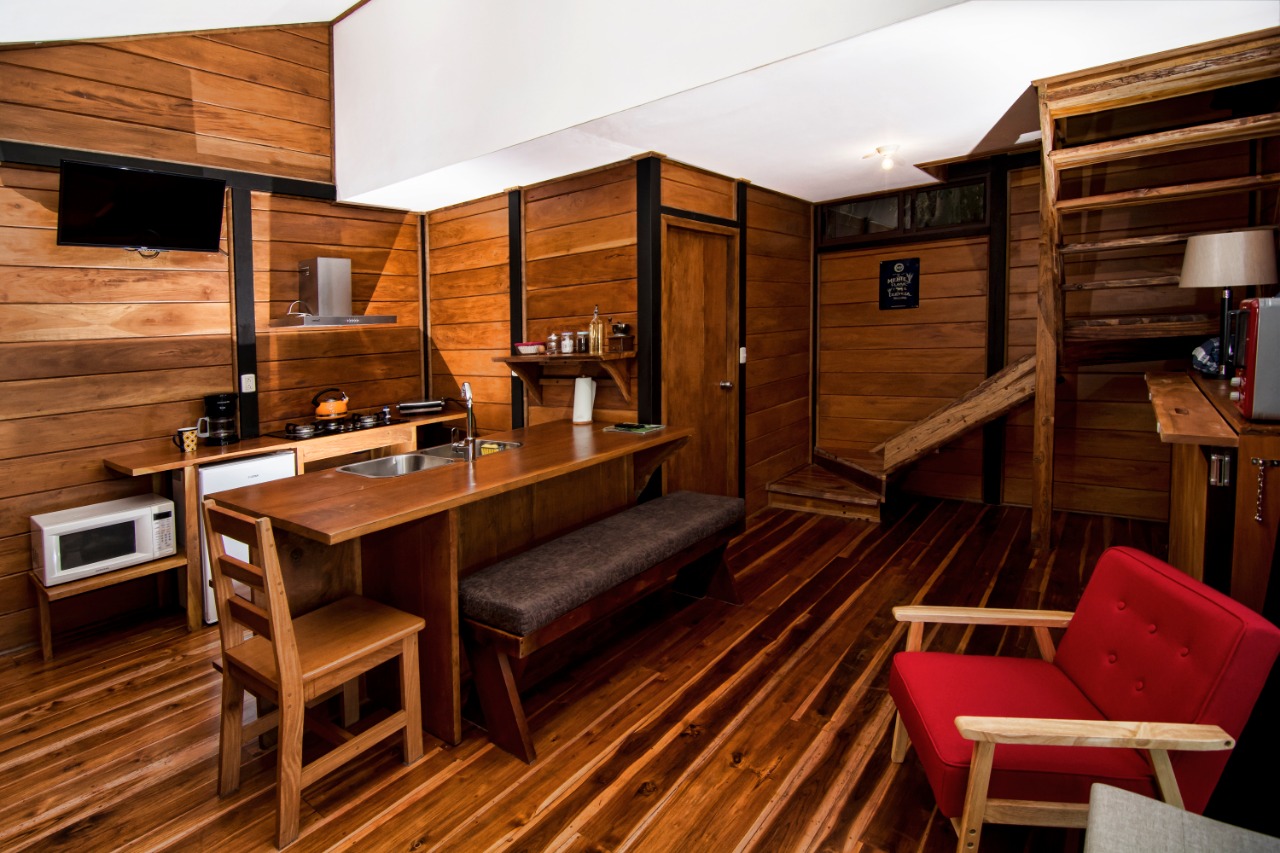 Cocina de la Guest House con barra de madera, televisión y escalera al segundo piso